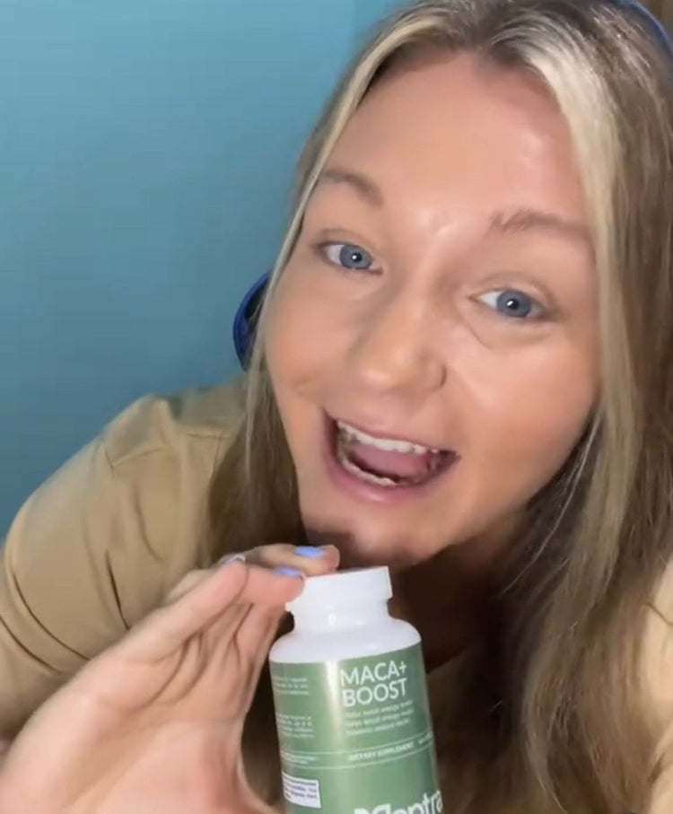 Person holding a bottle labeled 'Maca + Boost' by Peptrax against a blue background